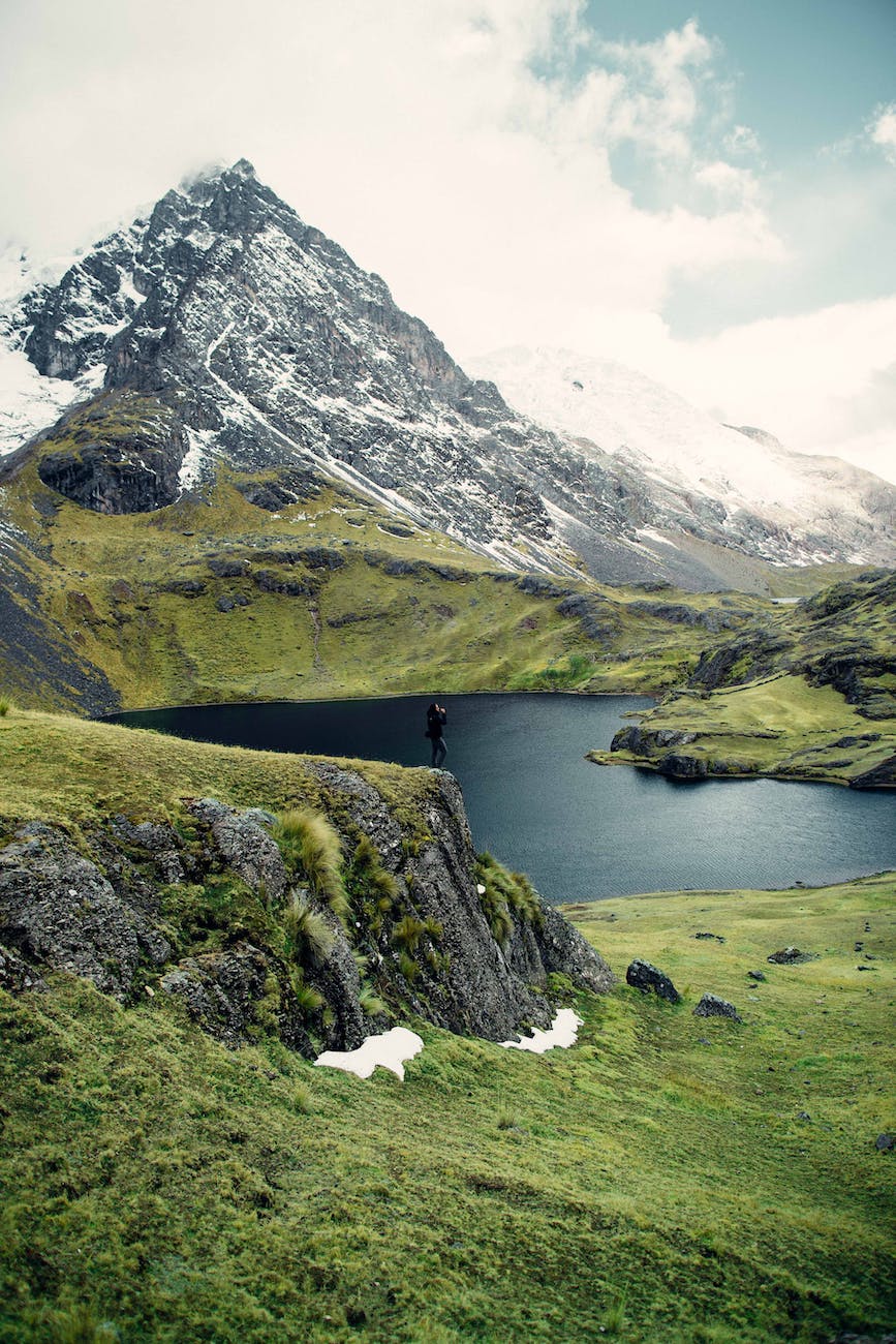 person standing on edge of cliff overlooking lake below